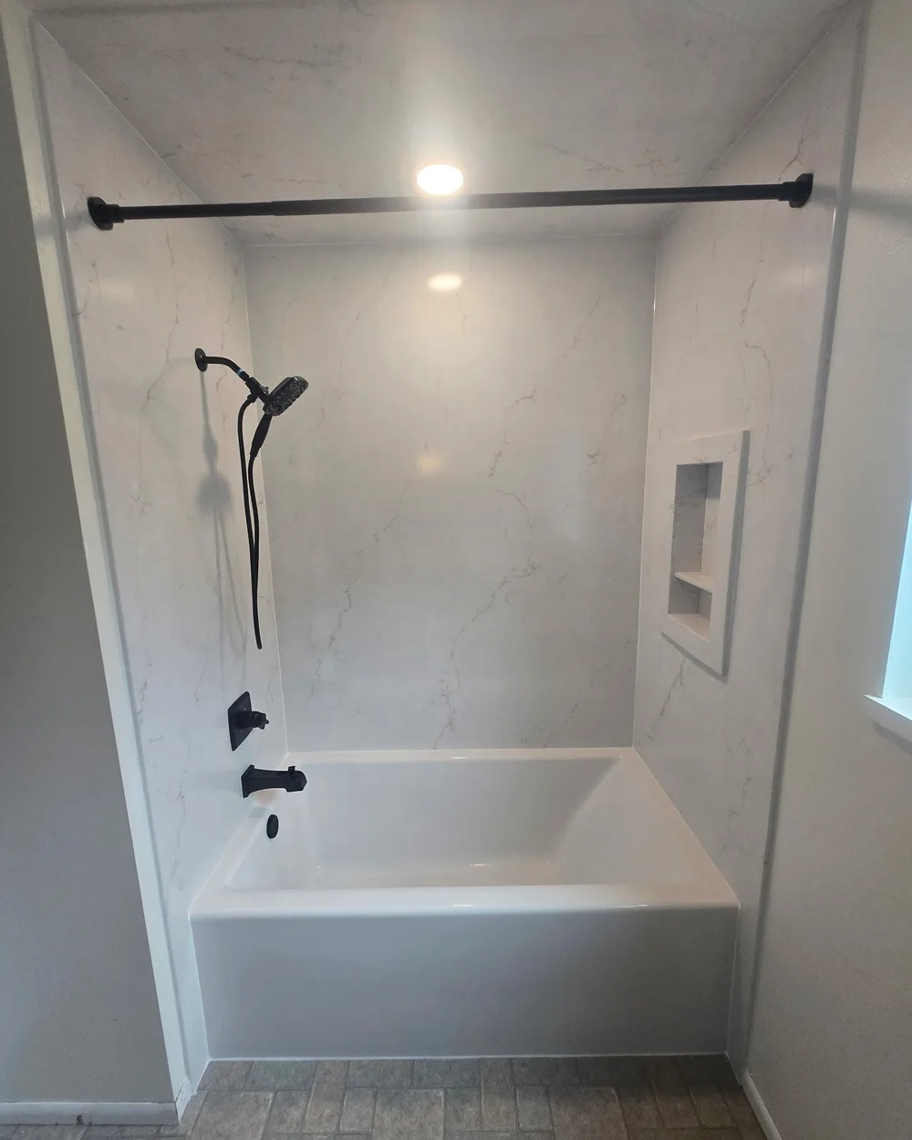 New white marble walk-in shower with matte black fixtures and recessed niche in Seattle