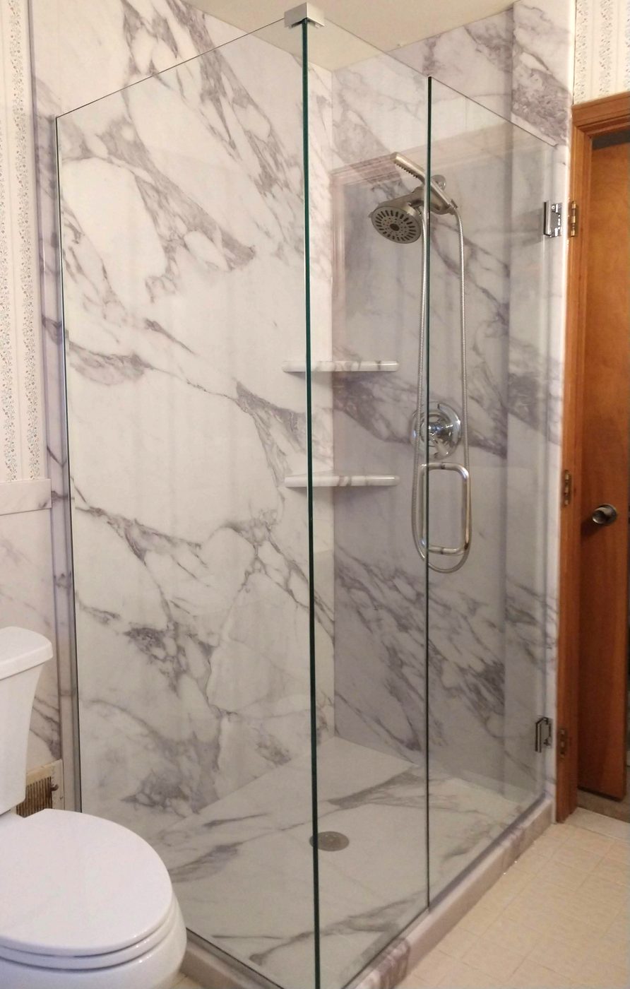 Tan tile walk-in shower with glass door and built-in shelving